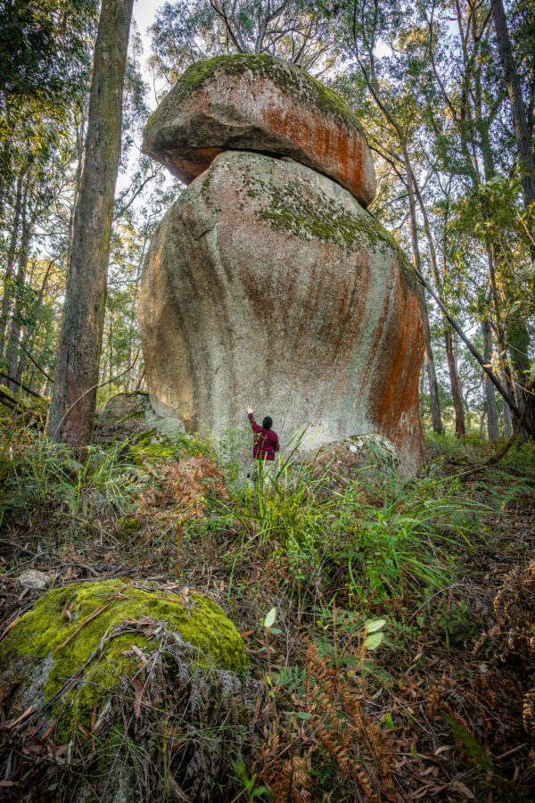 A man standing in front of a stack of granite boulders